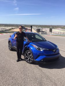 Hiroyuki Koba standing next to his prodigy, the 2018 Toyota C-HR, on a visit to Turn 1 at the Circuit of the Americas racetrack in Austin, Texas.